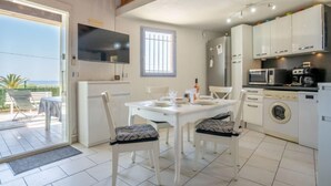 A modern kitchen with white appliances, a dining table with chairs, and a view of the outdoors.