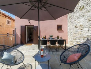 An outdoor patio with a table set for dining, two chairs, and a large umbrella providing shade. - Vacation home Negri by Interhome (Labin)