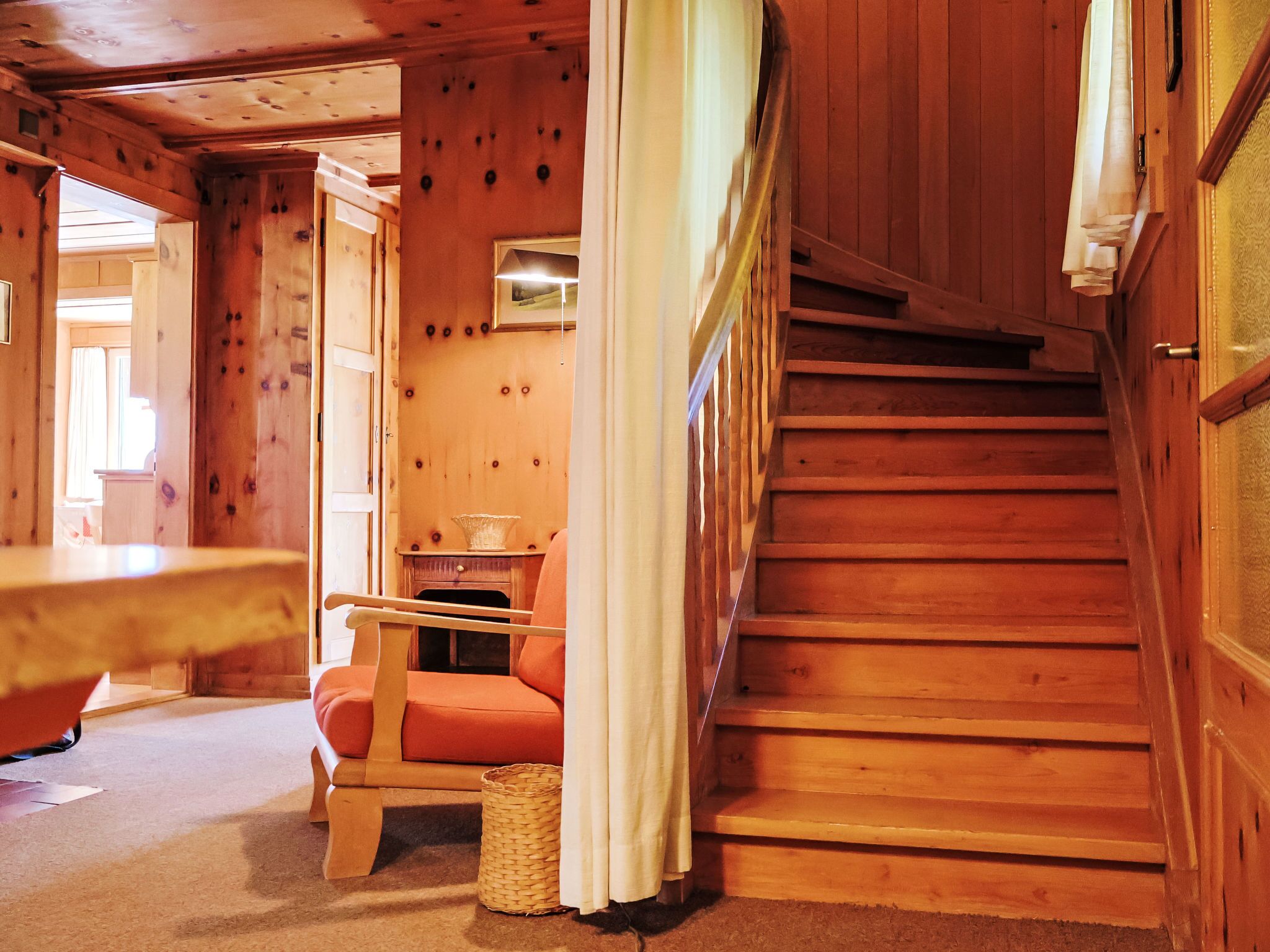 Ein Holzinnenraum mit Treppe, Stuhl und kleinem Tisch.