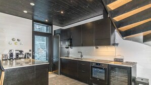 Een moderne keuken met donkere kastjes, een inbouwoven en een koffiehoek.