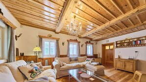 Una sala de estar acogedora con vigas de madera, una mesa de centro de cristal y un conjunto de sofás.
