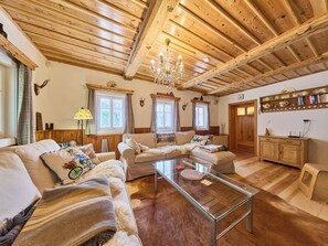 A cozy living room with wooden beams, a glass coffee table, and a sofa set.
