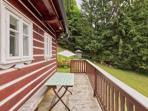 A wooden cabin with a balcony, a table, and an umbrella.