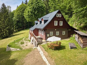 Eine Holzhütte mit Veranda, einem Esstisch mit Stühlen und einer überdachten Sitzgruppe im Freien.