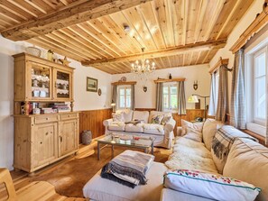 Ein gemütliches Wohnzimmer mit Holzbalken, einer Deckenleuchte und einer Sofagarnitur.