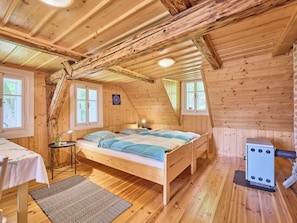 A cozy, wooden cabin bedroom with a loft bed, a small table with a lamp, and a fireplace.