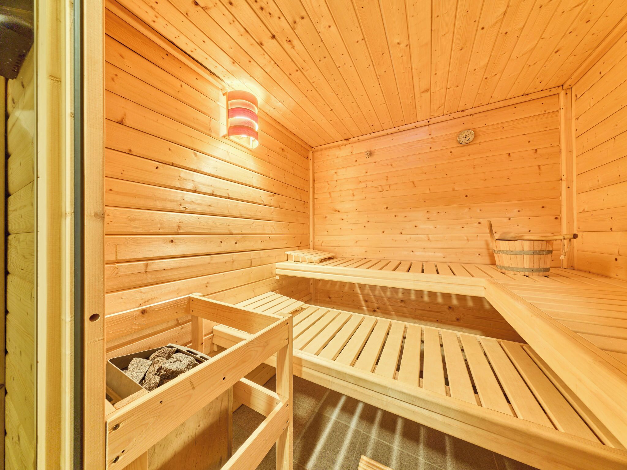 A wooden sauna with benches and a bucket.