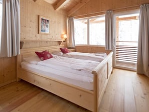 Un dormitorio de cabaña de madera con dos camas, una ventana con persianas y un póster en la pared.