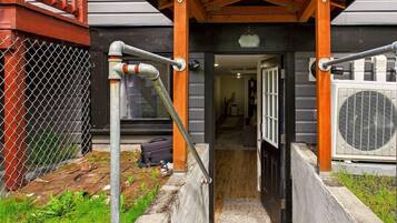 A covered entrance with a wooden porch, a metal gate, and an air conditioning unit.