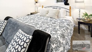 A bedroom with a bed, bedside tables, a lamp, a window with curtains, and a wall-mounted light fixture. - AC*Boutique Apt. Albany dwntn*KING*Queen*Full* 1 bath. PNW (Albany)