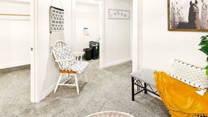 A hallway with a macrame wall hanging, a white chair, a small table, and a framed picture of llamas on the wall. - AC*Boutique Apt. Albany dwntn*KING*Queen*Full* 1 bath. PNW (Albany)