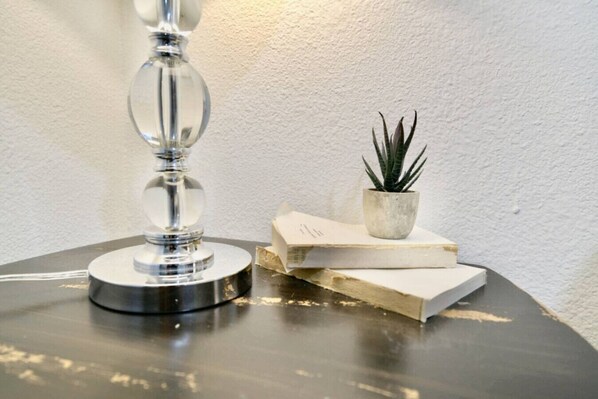 A table with a lamp, a potted plant, and stacked books.