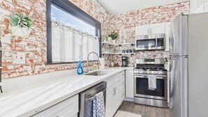 A kitchen with a brick wall, stainless steel appliances, and white cabinetry. - Stay right downtown at a historical updated property (Albany)