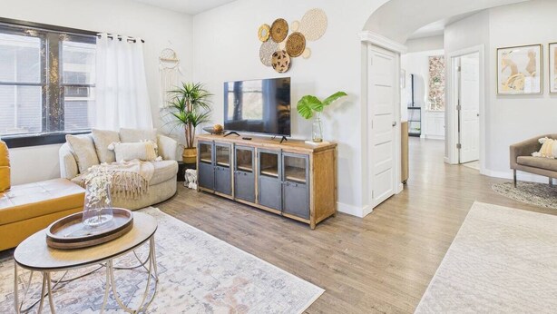 A modern living room with a sofa, a coffee table, a TV on a wooden cabinet, and decorative wall art. - Stay right downtown at a historical updated property (Albany)