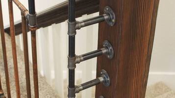 A wooden staircase railing with a metal handrail and a dark wooden base.