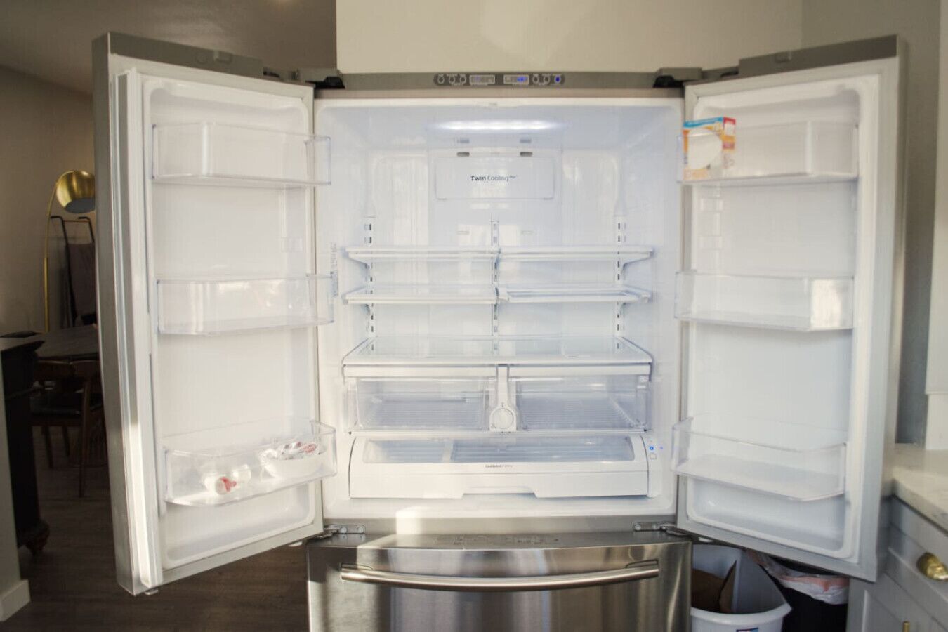 An open refrigerator with multiple shelves and a stainless steel freezer compartment.