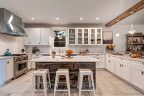 A modern kitchen with white cabinets, a large island, and a built-in oven.