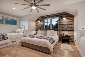 Un dormitorio con una cama grande, dos mesitas de noche, un ventilador de techo y una ventana.