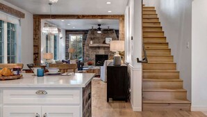 A kitchen with a wooden staircase, a stone fireplace, and a dining area with a view of the outdoors. - Abode at Palomino Ridge, amazing views, nature (Jackson)