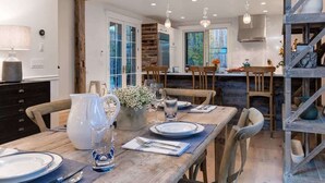 A dining area with a wooden table set for four, a kitchen in the background, and a staircase with a rustic design. - Abode at Palomino Ridge, amazing views, nature (Jackson)