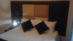 A hotel room with a bed, pillows, a nightstand, and a headboard. - dejazzy guest house (Johannesburg)