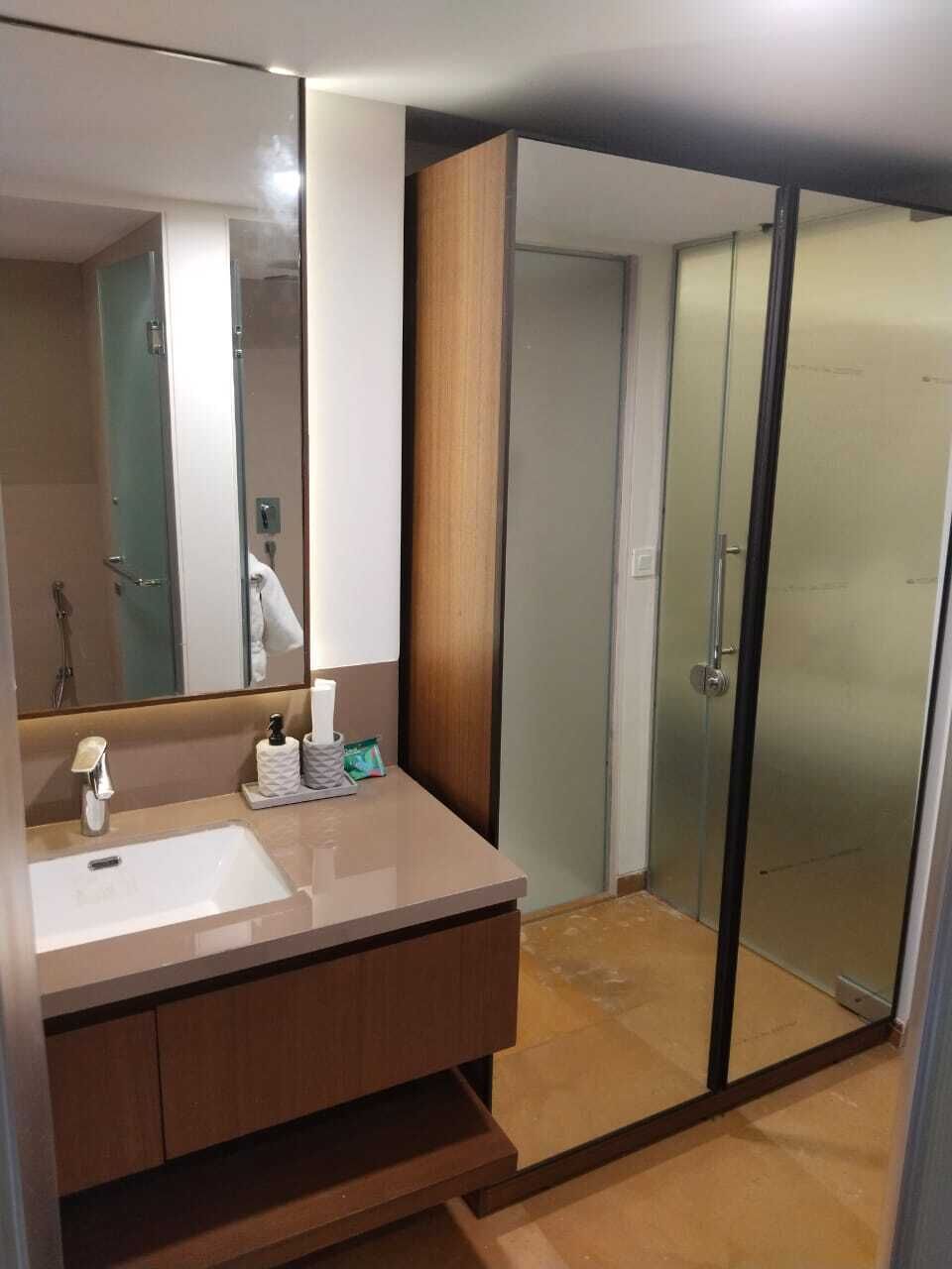 A modern bathroom with a large mirror, a sink, and a shower area.
