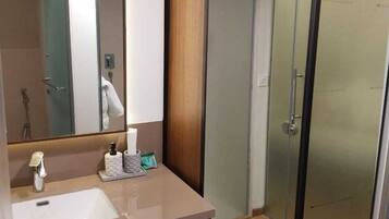 A modern bathroom with a large mirror, a sink, and a shower area.