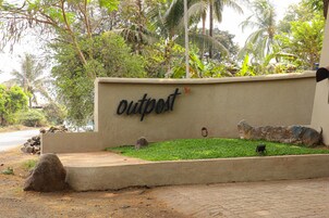 Un letrero con la palabra 'outpost' en una pared, rodeado de vegetación y rocas.