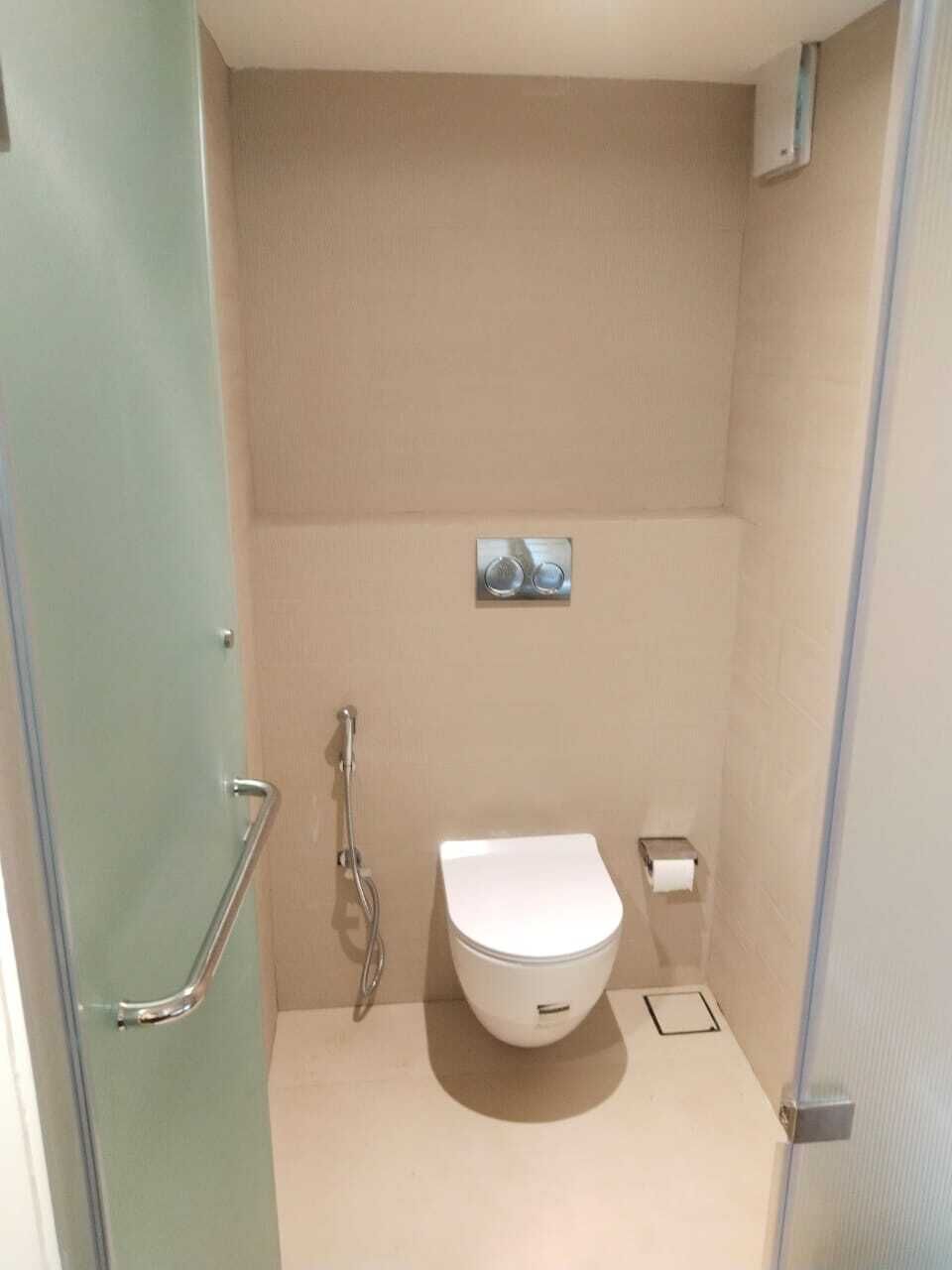 A small, enclosed bathroom with a toilet, a shower, and a towel rack.