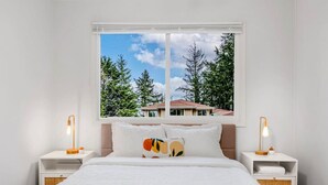 A bedroom with a bed, two bedside tables, a window with a view of trees and a house, and two lamps. - 1803 Renton · 2b1b Sweet Suite @Renton 10 mins to SeaTac airport (Renton)