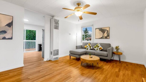 A modern living room with hardwood flooring, a gray sofa with decorative pillows, a round coffee table, and a ceiling fan. - 1803 Renton · 2b1b Sweet Suite @Renton 10 mins to SeaTac airport (Renton)