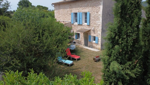 A stone building with blue shutters, a grassy yard, and a red chair. - Views of Sault, cycling, hiking, Mont Ventoux (Sault)