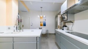 Una cucina moderna con isola centrale, elettrodomestici in acciaio inossidabile e una lampada a sospensione.