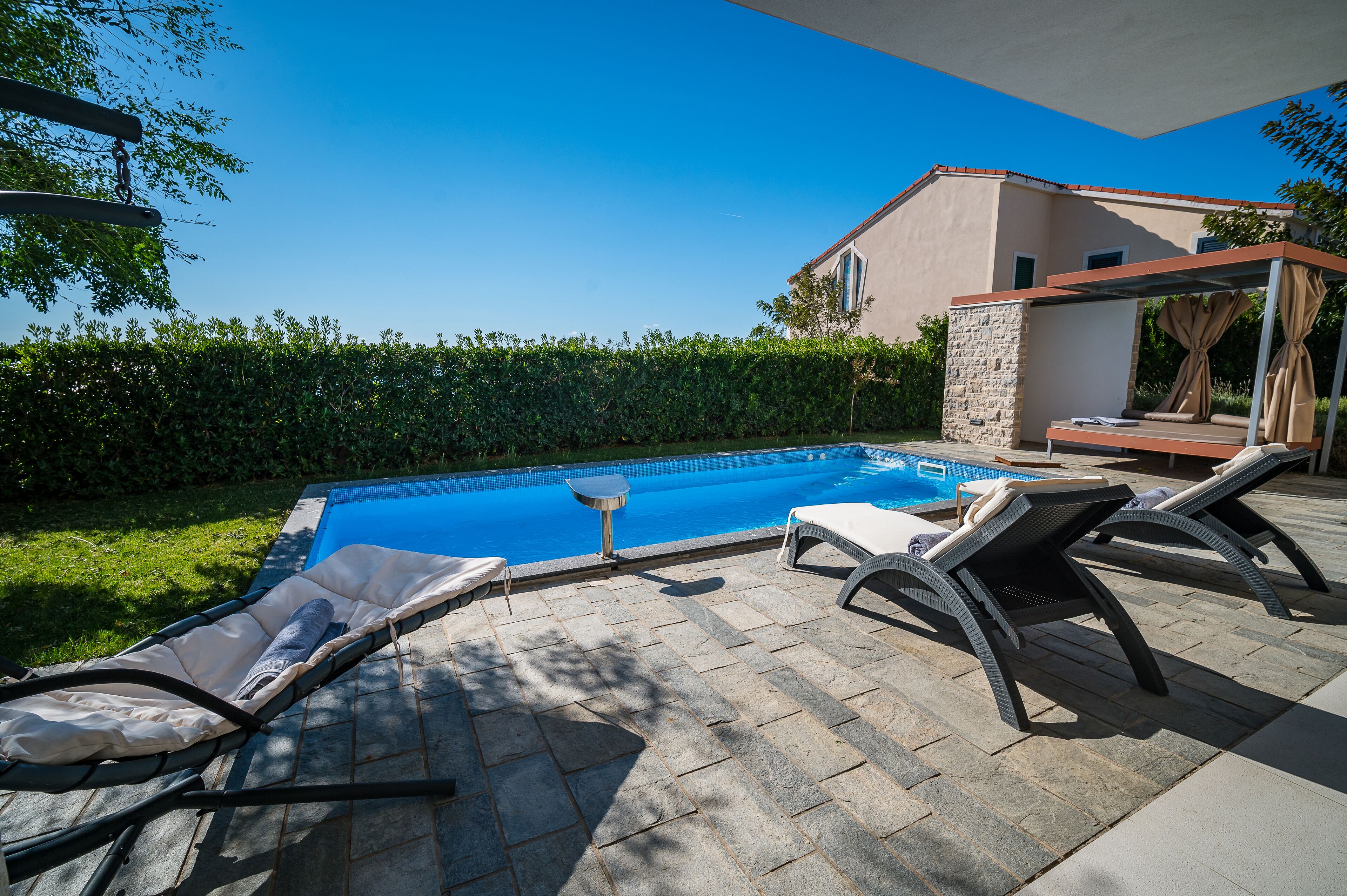 A swimming pool with lounge chairs and a pergola.