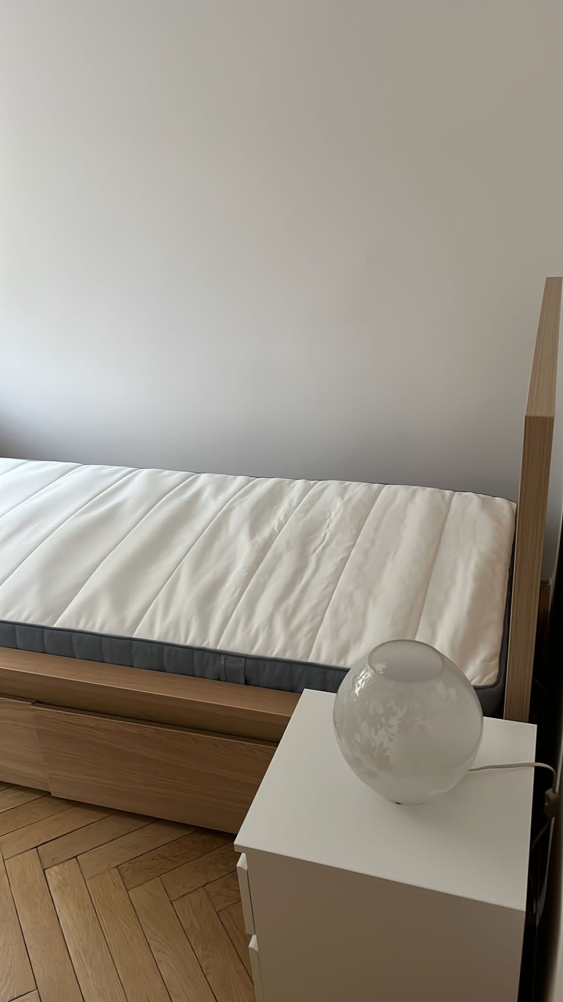 Une chambre à coucher avec un lit, une table de chevet et une lampe.