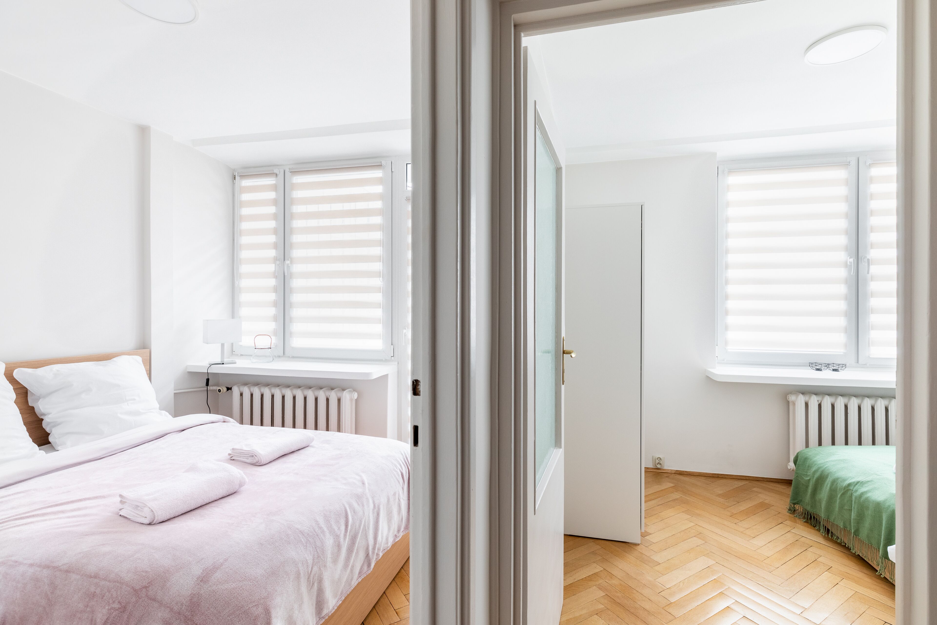 A modern bedroom with a bed, a radiator, and a window with blinds.