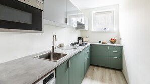 Een moderne keuken met een roestvrijstalen spoelbak, een ingebouwde oven en een raam boven de spoelbak.