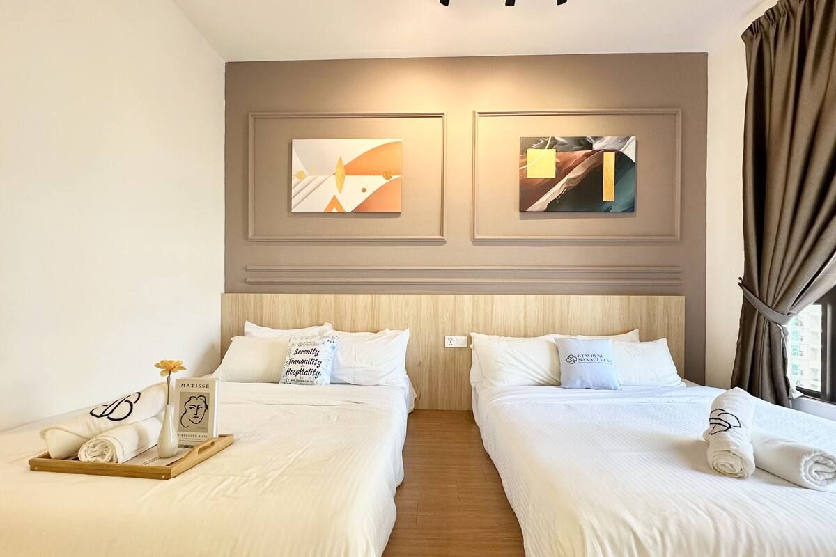 Une chambre d’hôtel avec deux lits, une tête de lit en bois et des œuvres d’art accrochées au mur.