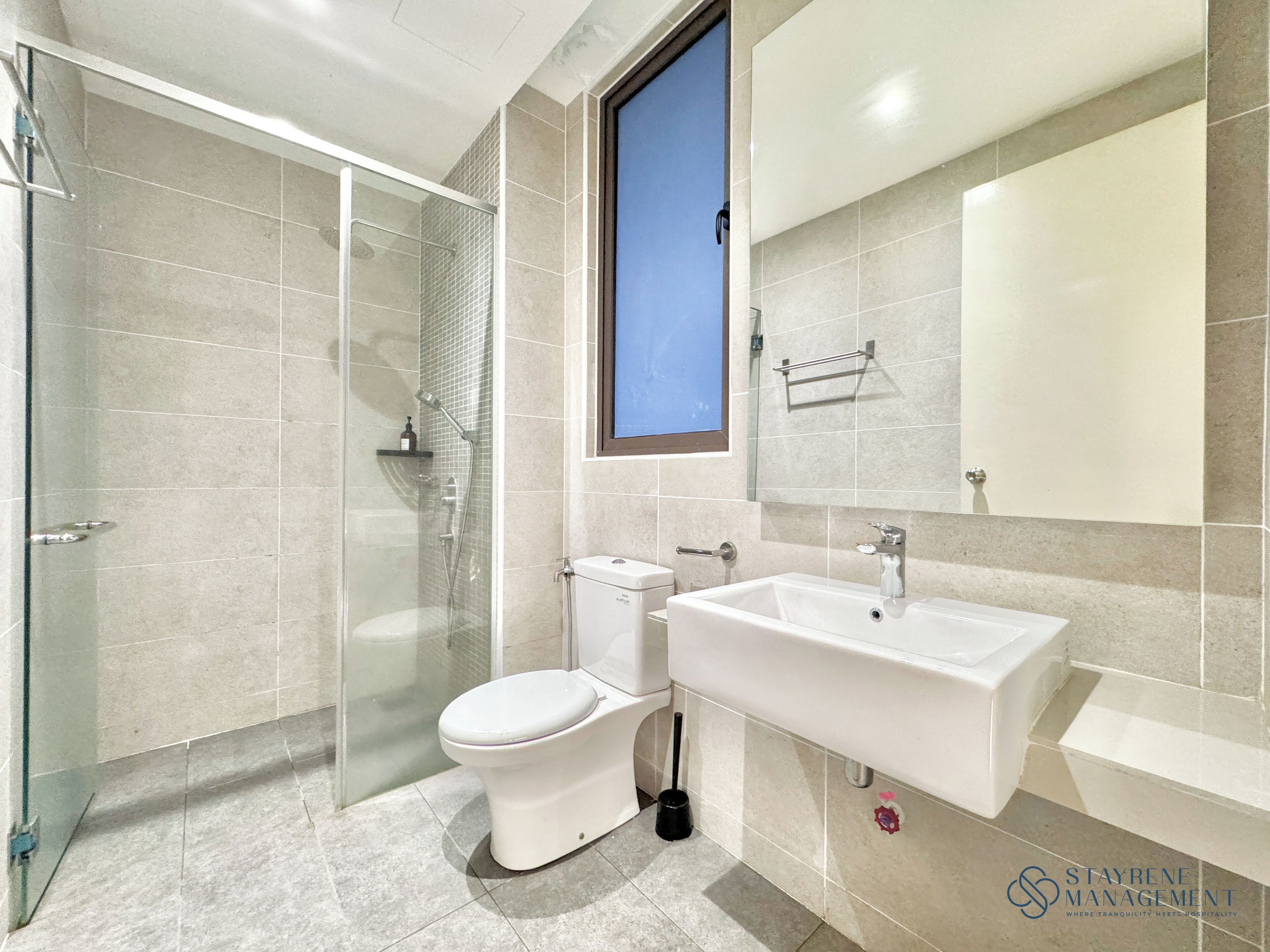 Un baño moderno con cabina de ducha de vidrio, inodoro y lavabo con espejo.