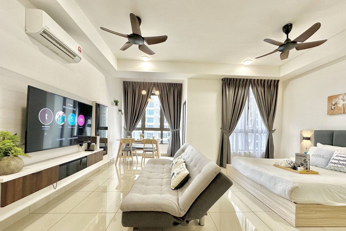 Une chambre d’hôtel moderne équipée d’un canapé, d’un lit, d’un coin repas et de deux ventilateurs de plafond.