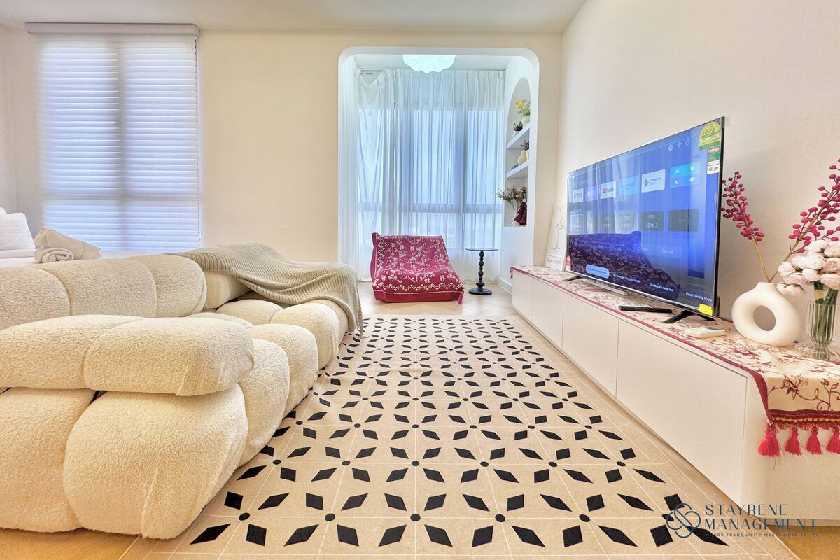 Un salon moderne avec un canapé, un téléviseur et un sol à motifs.