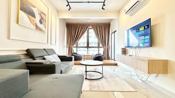 A modern living room with a grey sofa, a round coffee table, and a TV mounted on the wall.
