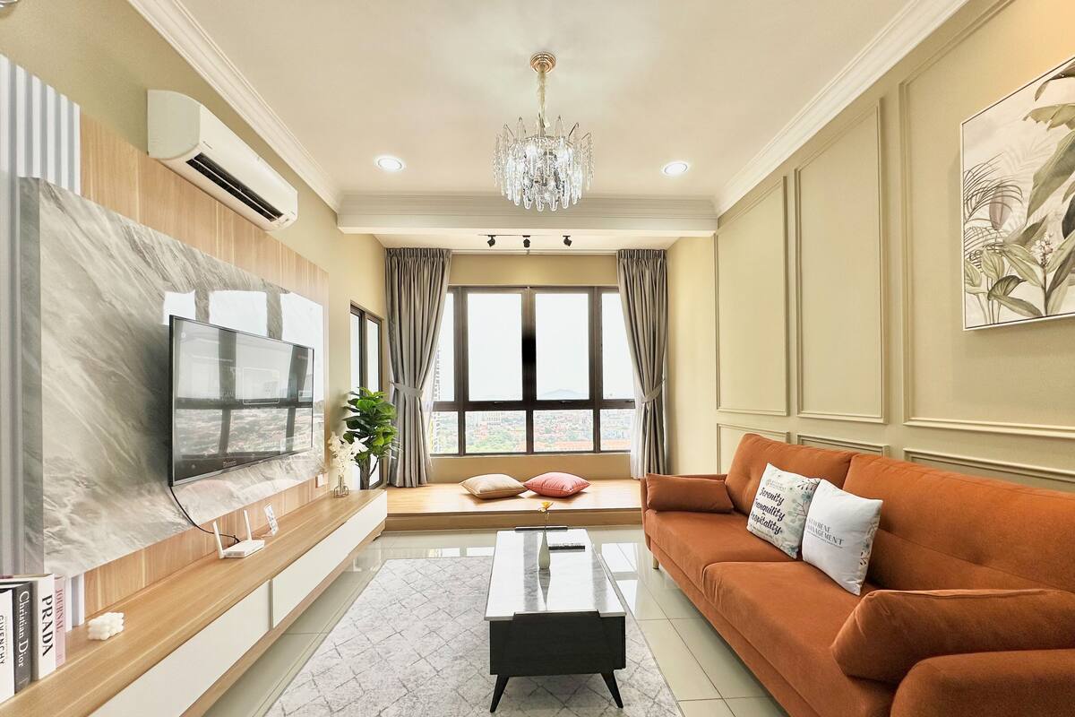 Un salon moderne doté d’un grand téléviseur à écran plat, d’une console en bois, d’une table basse noire et d’un confortable canapé orange.
