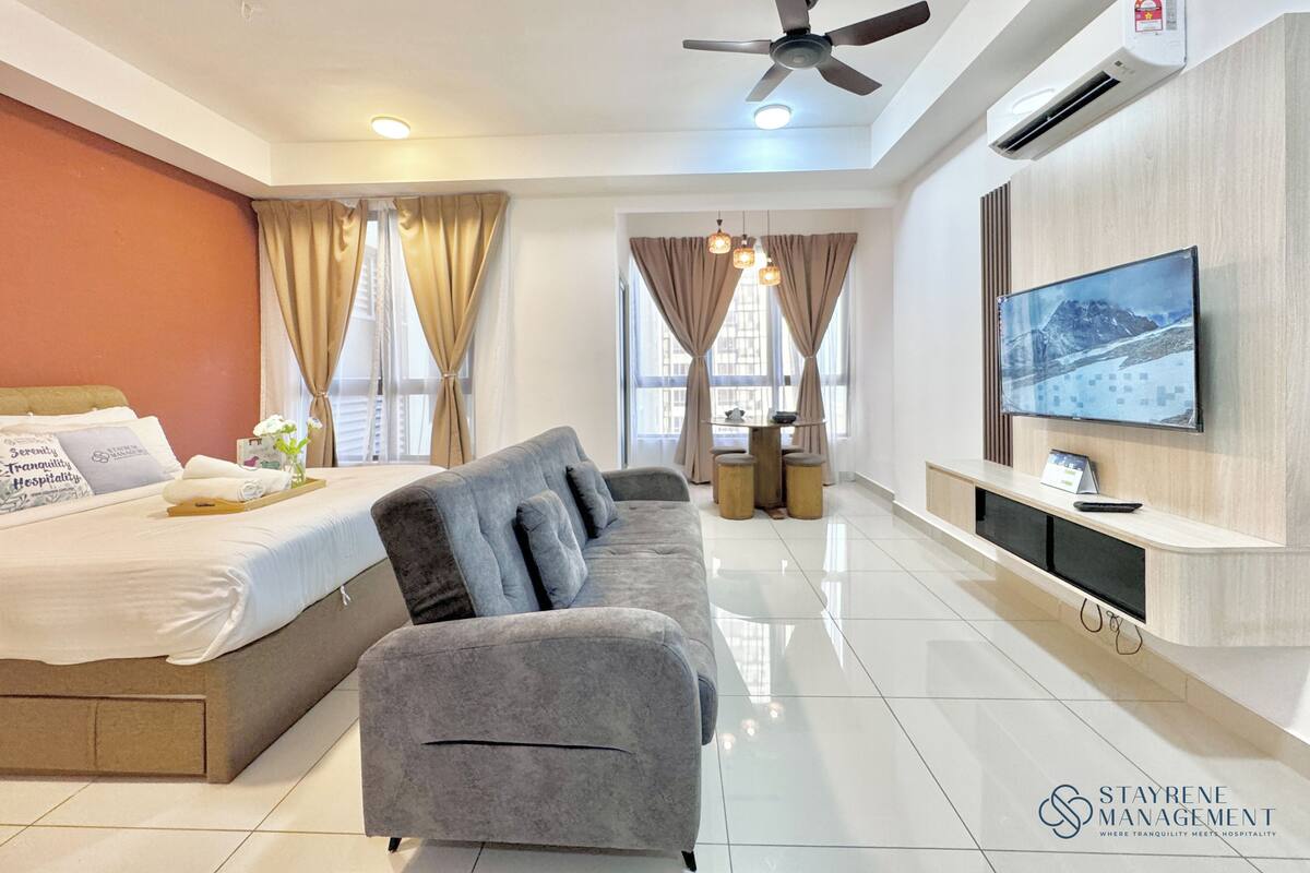 Une chambre d’hôtel moderne équipée d’un lit, d’un canapé, d’une télévision et d’un coin repas.