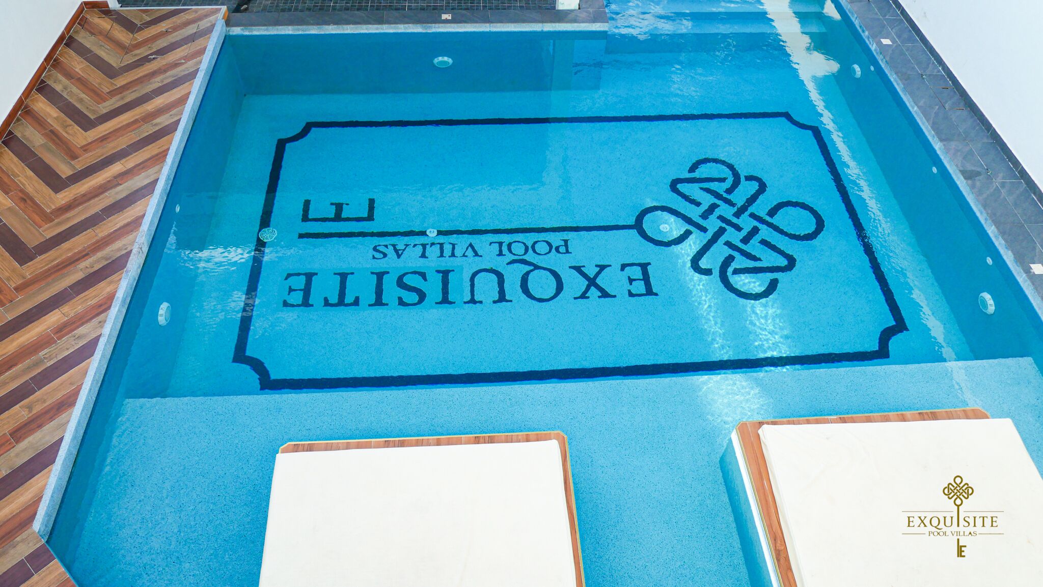 A swimming pool with a logo and text indicating it is part of the Exquisite Pool Villas.