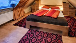 Ein Schlafzimmer mit einem Bett, zwei Nachttischen, einem Fenster mit Vorhängen und einer Heizung.