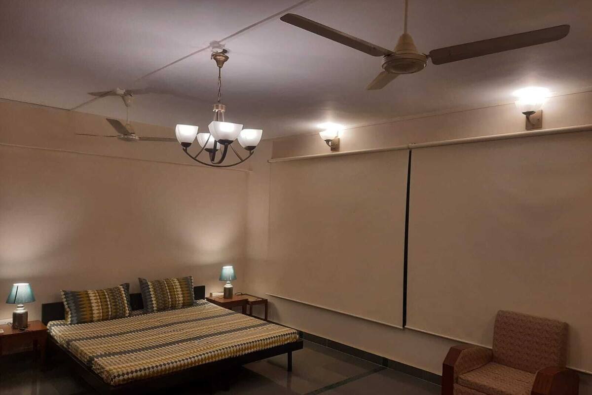 Ein Schlafzimmer mit einem Bett, Nachttischen, einem Sessel, einem Deckenventilator und einer Wandleuchte.