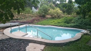 Piscina com escada de metal e deck de concreto.