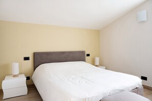 A bedroom with a bed, nightstands, and a wall-mounted light fixture.