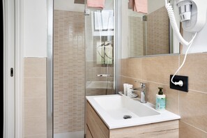 Ein Badezimmer mit einem weißen Waschbecken, einem Spiegel, einem Haartrockner und einer Shampoo-Flasche.